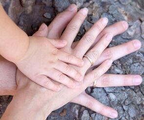 Two adult hands and one child hand all in