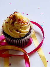 Chocolate cupcake with yellow frosting w/ ribbons & confetti